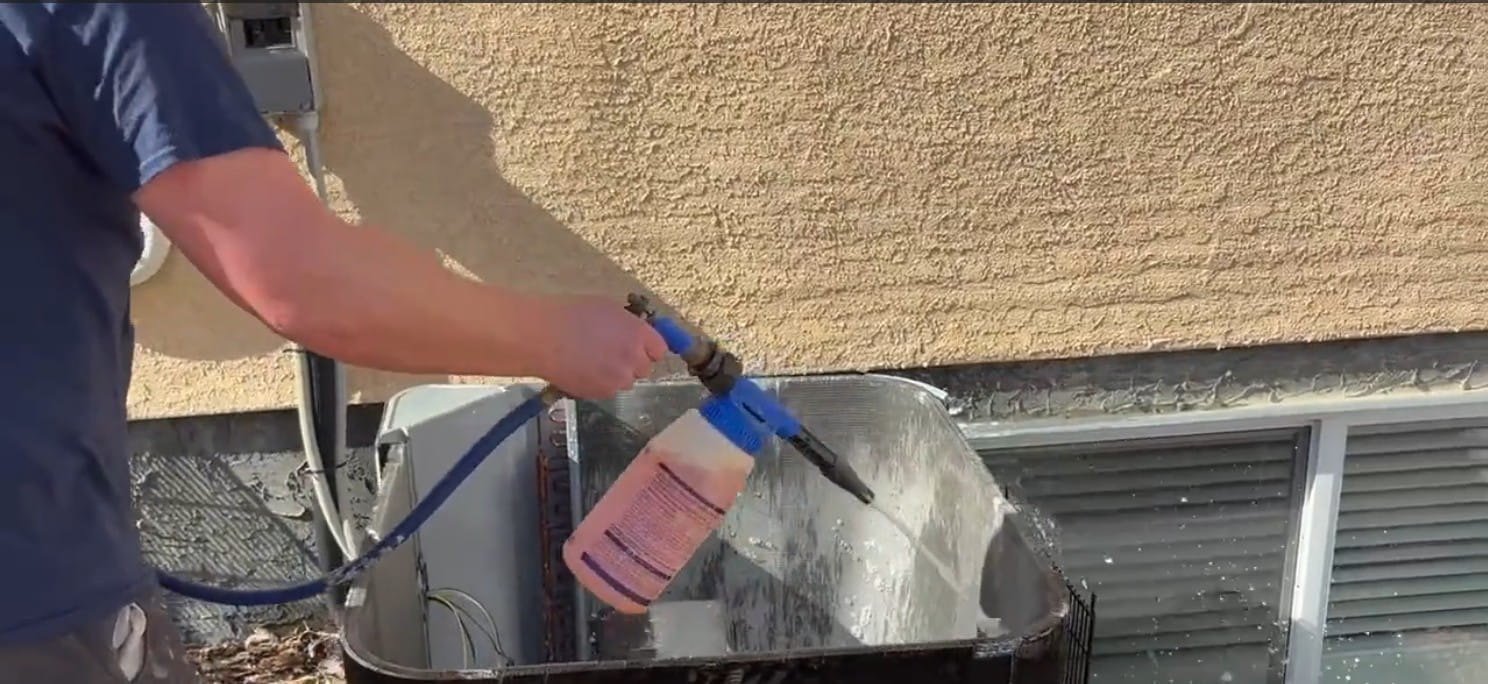 AC Clean technician servicing an outdoor air conditioner condenser